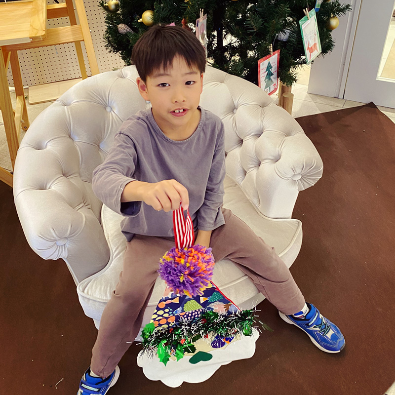 【写真】ワークショップで制作した作品を持ちカメラに笑顔を向けている子ども